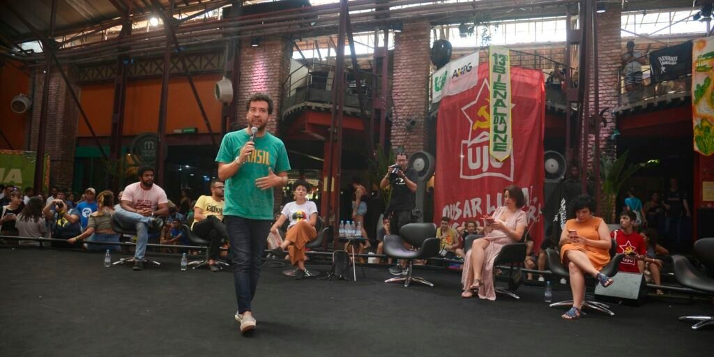 André Janones fala ao microfone em debate da Bienal da UNE