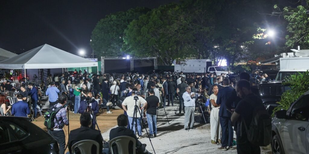 Área reservada à imprensa à noite, com jornalistas e câmeras