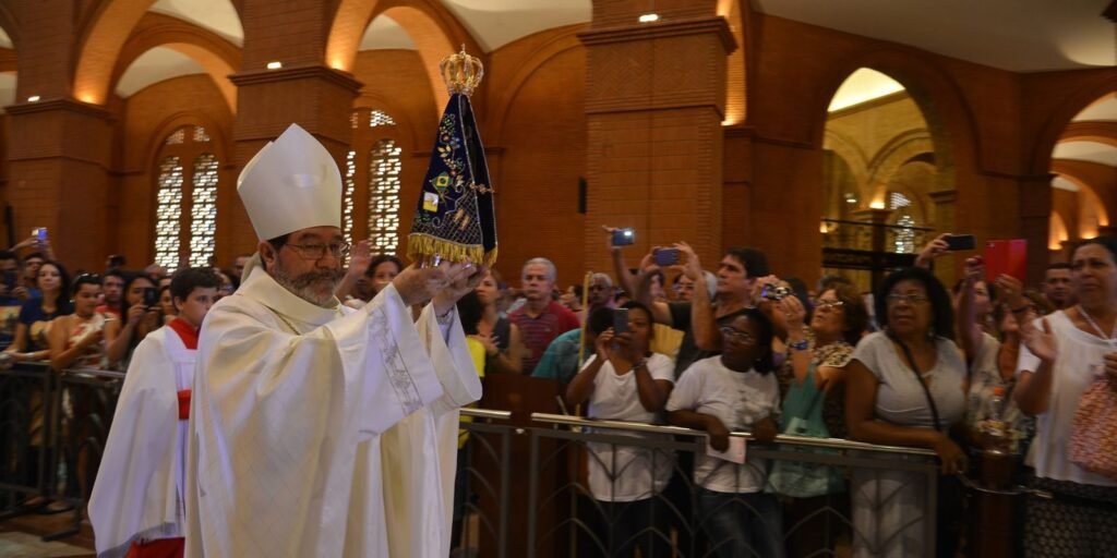 Celebrante ergue imagem de Nossa Senhora Aparecida durante missa