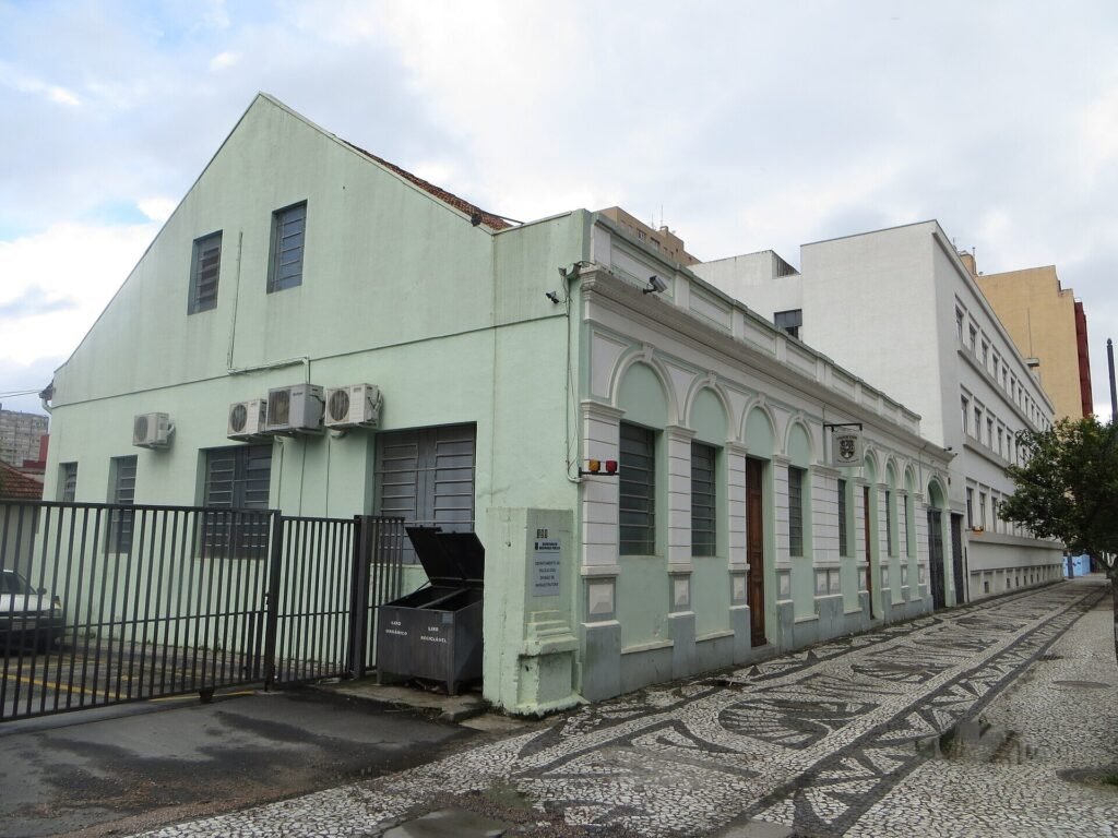Prédio verde-claro de dois andares com portão de grade