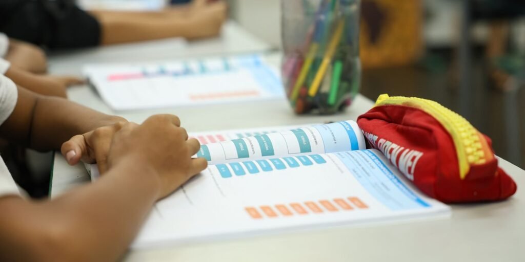 Mesas de sala de aula com cadernos de atividades e estojo