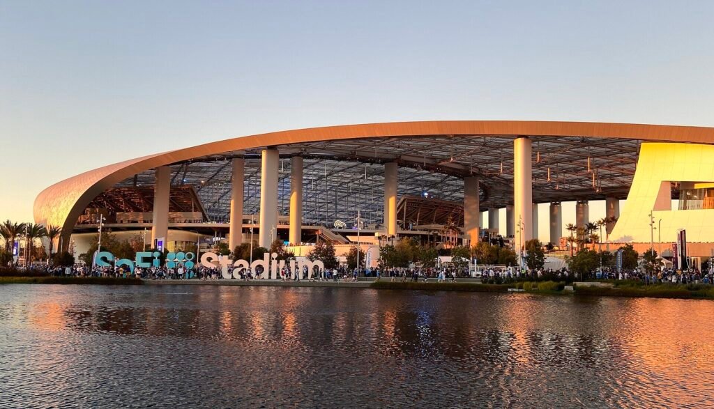 Fachada do SoFi Stadium refletida em um lago ao entardecer