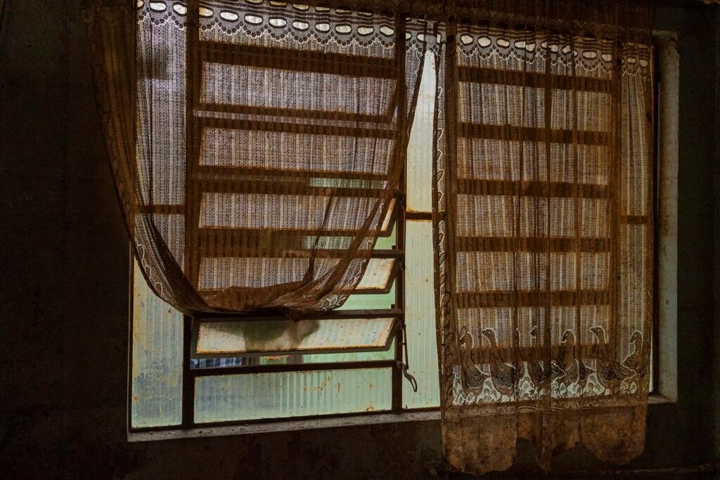 Janela com cortinas sujas de barro em casa atingida pela enchente em São Leopoldo (RS)