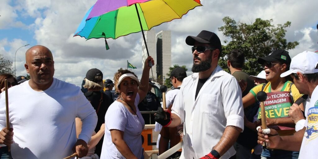 Manifestantes de branco tocam tambores em ato da enfermagem