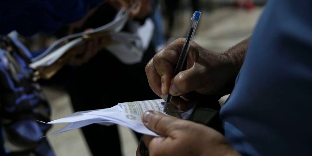 Mão segurando caneta sobre formulário de justificativa eleitoral