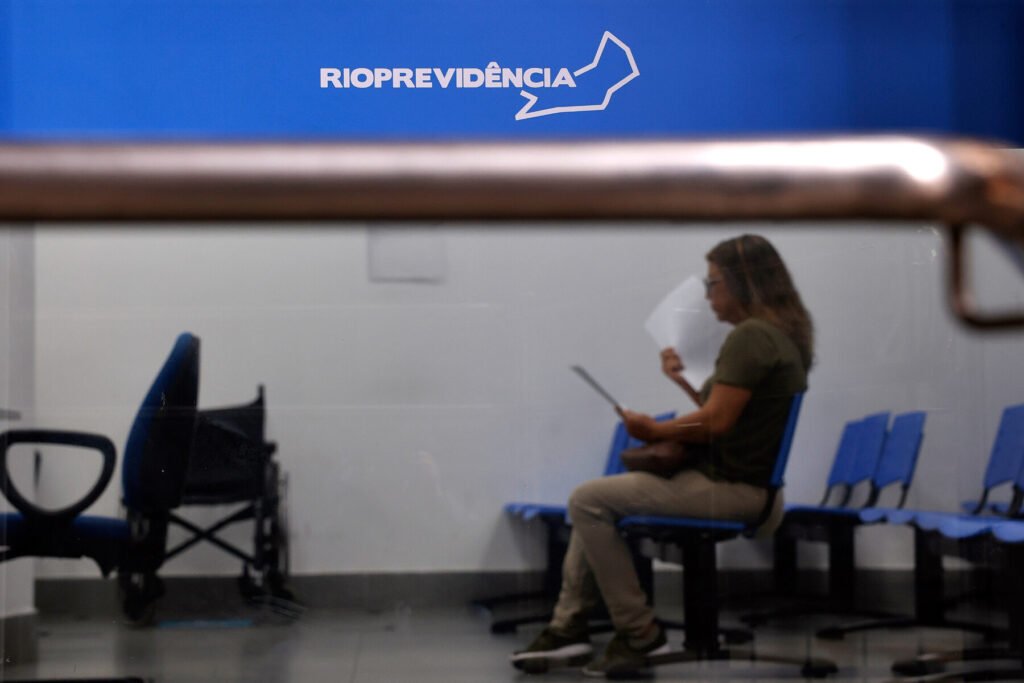 Mulher lê documento sentada na sala de espera de agência do Rioprevidência