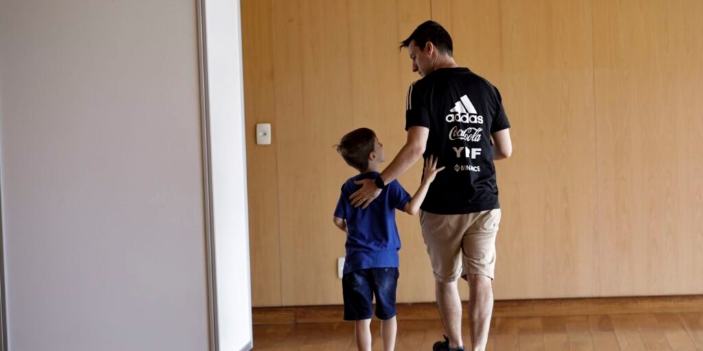 Pai e filho vão para a cabine de votação na embaixada da Argentina em Brasília, em eleição de argentinos no Brasil