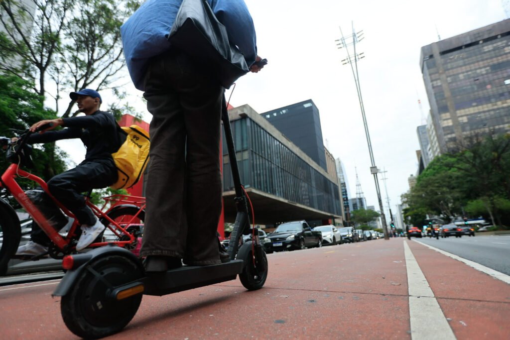Patinete elétrico e bicicleta elétrica de entregador em ciclovia de São Paulo