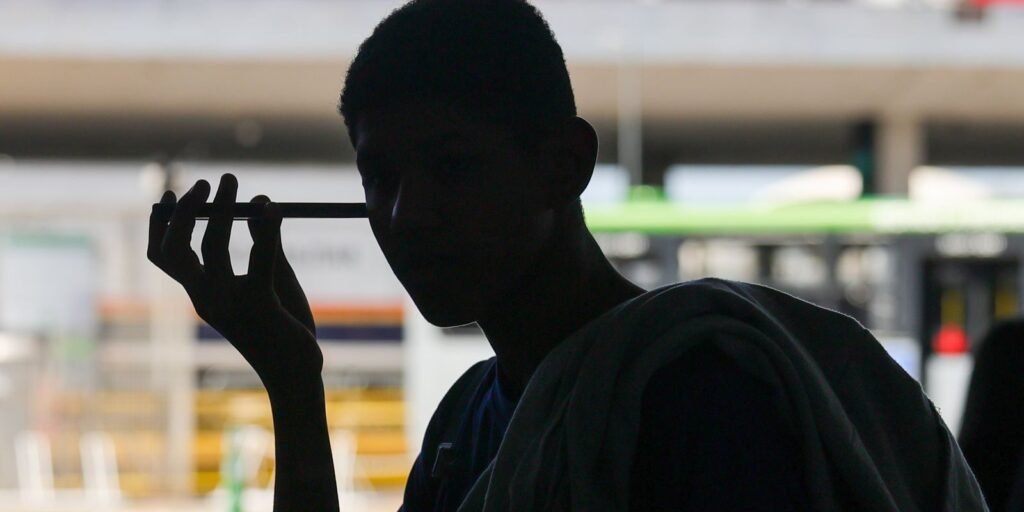 Pessoa ouve áudio no celular na Rodoviária do Plano Piloto, em Brasília