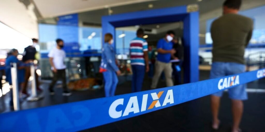 Pessoas em fila na entrada de uma agência da Caixa
