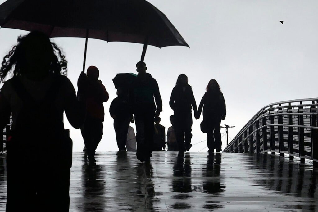 Pessoas na rua durante tarde com muita chuva na região do Ibirapuera