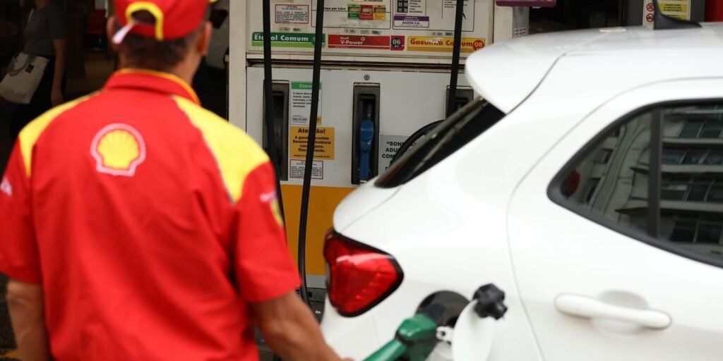Frentista abastece carro branco em posto