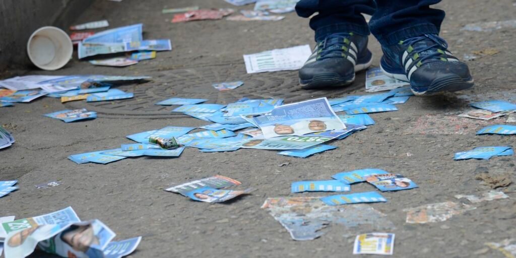 Santinhos de políticos jogados em frente a escola municipal na Maré, zona norte do Rio de Janeiro