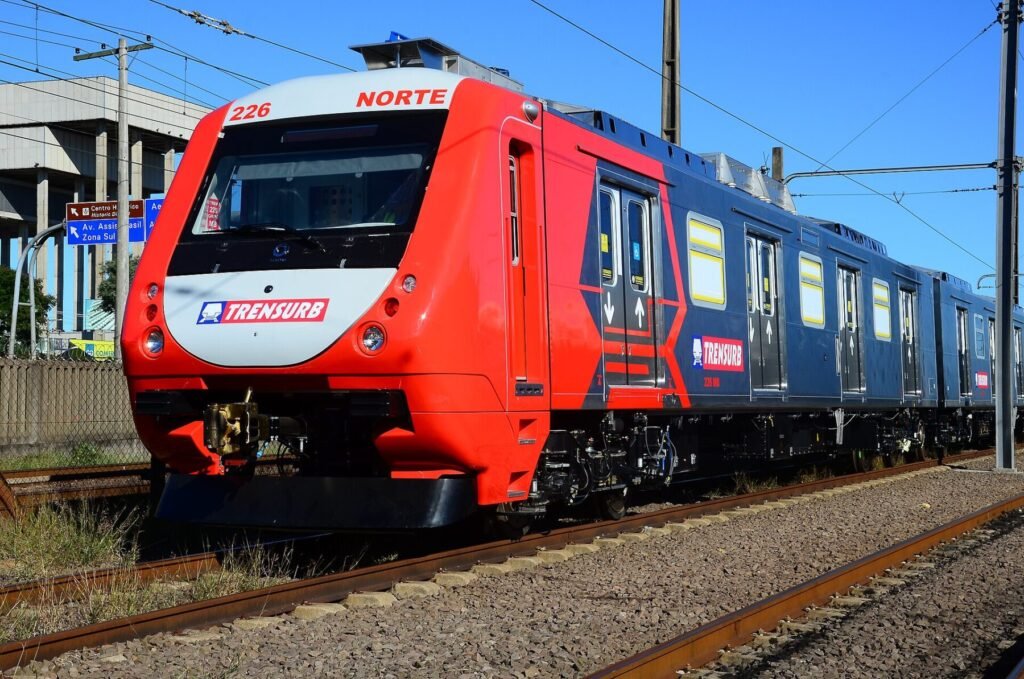 Trem vermelho e azul da Trensurb nos trilhos