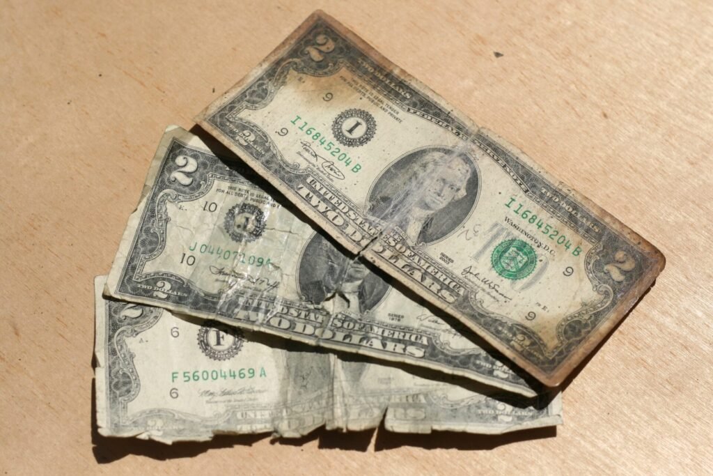 Três notas de 2 dólares gastas sobre uma mesa