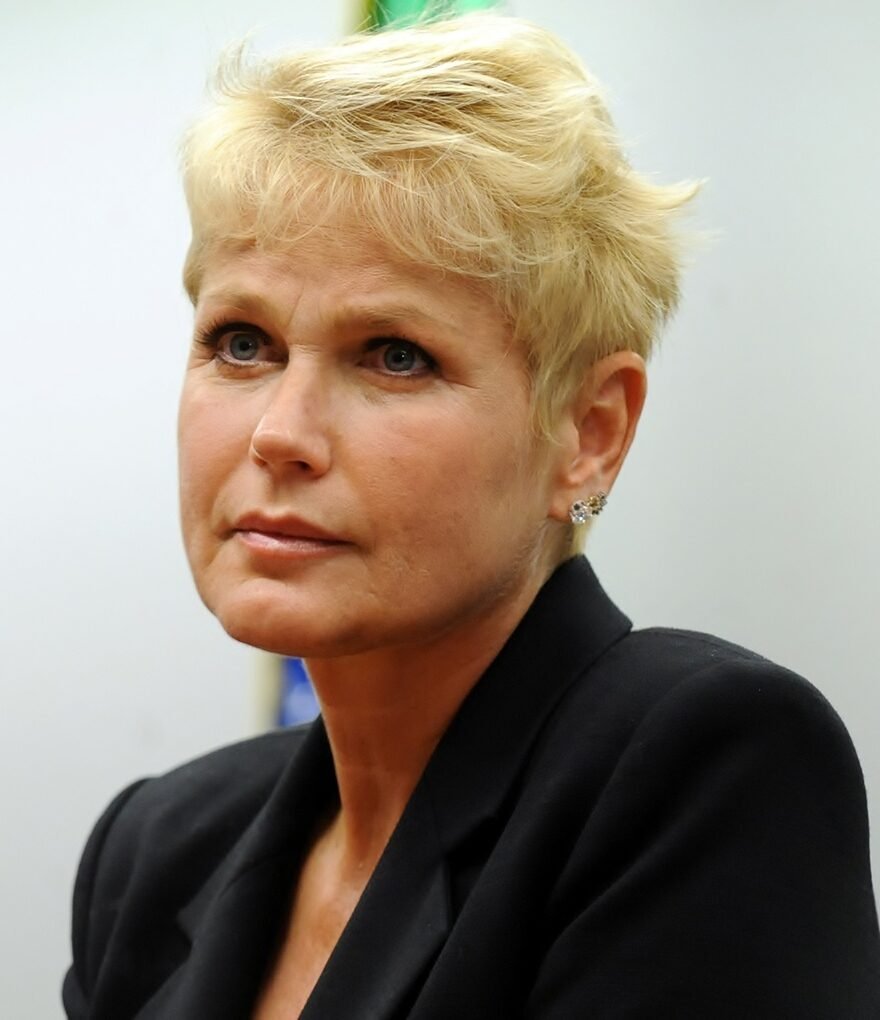 Xuxa Meneghel, de cabelo curto loiro e blazer preto